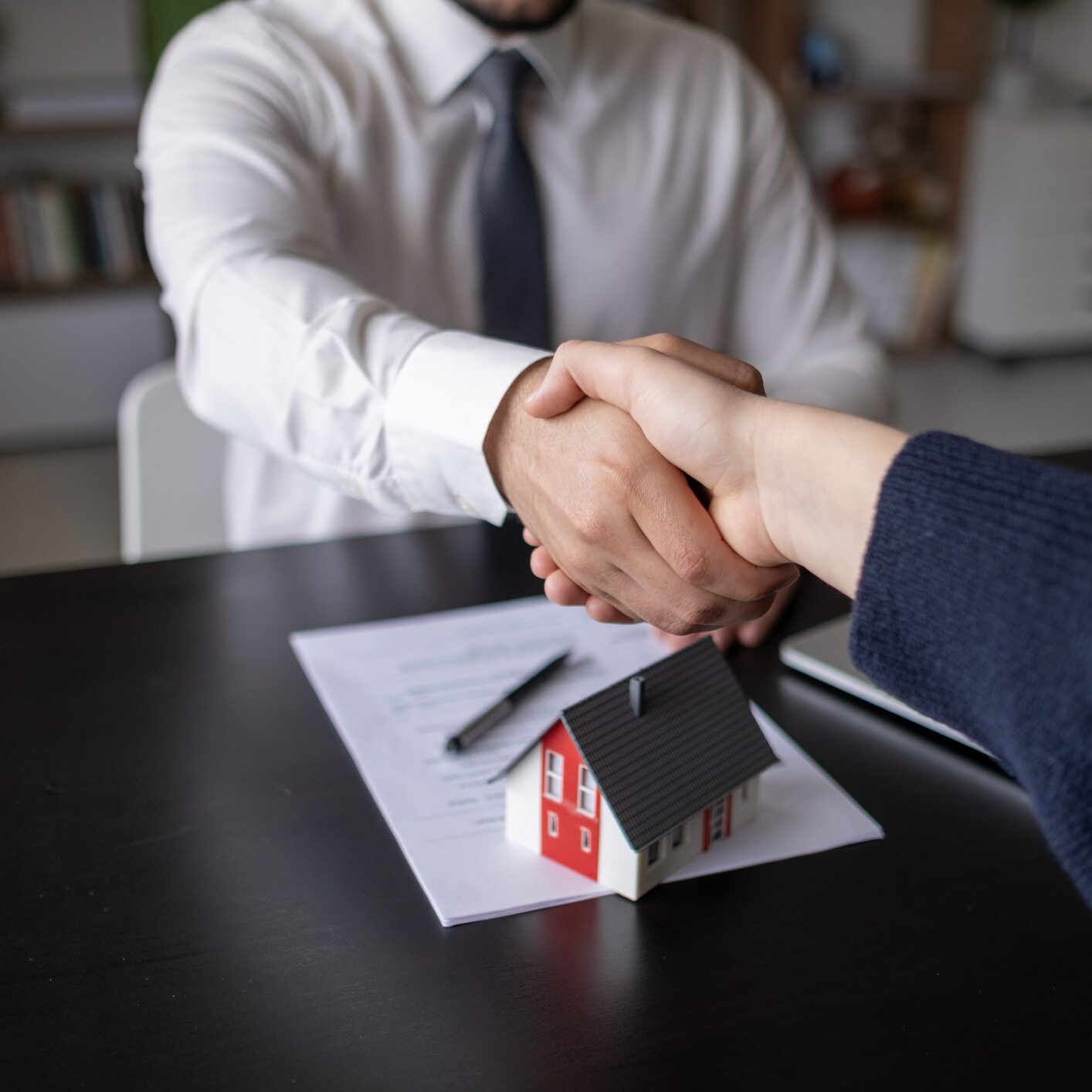 Real estate agents shake hands after the signing of the contract agreement is complete.